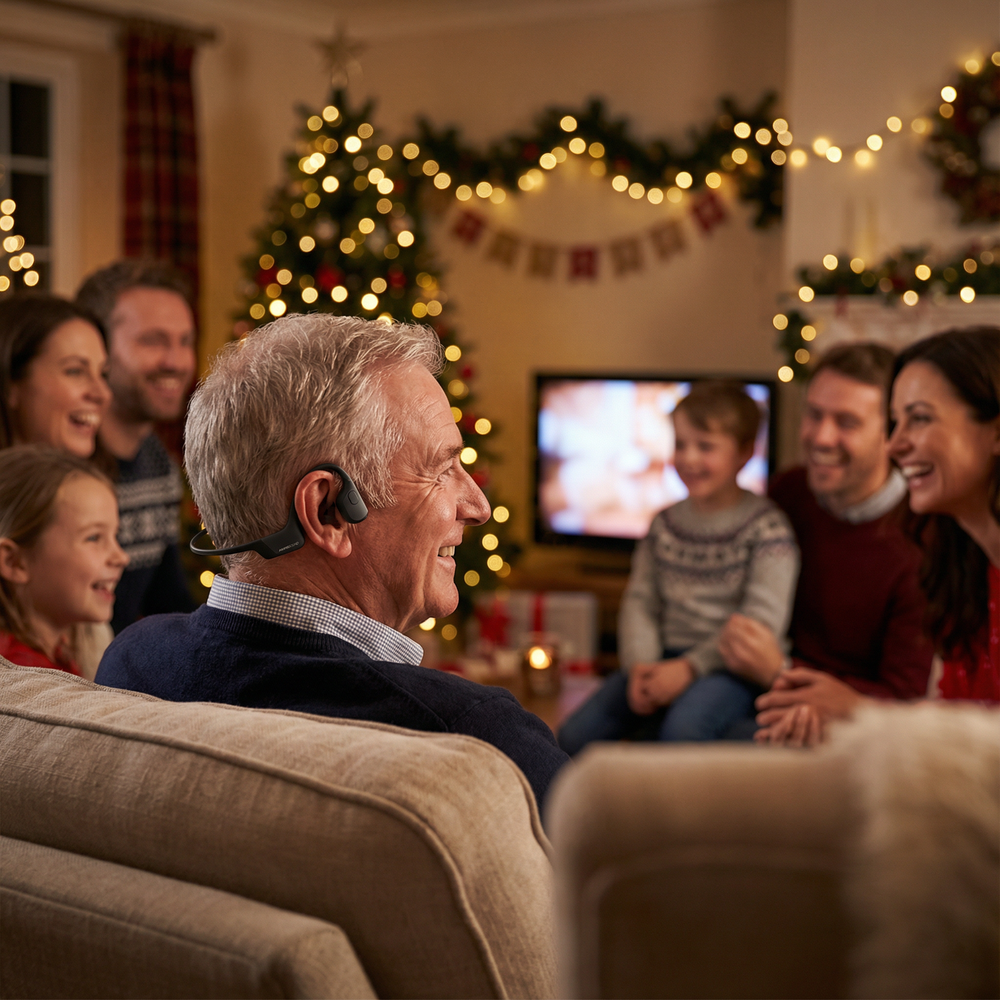 Man wearing hearing assist earphones enjoying Christmas movie night with family